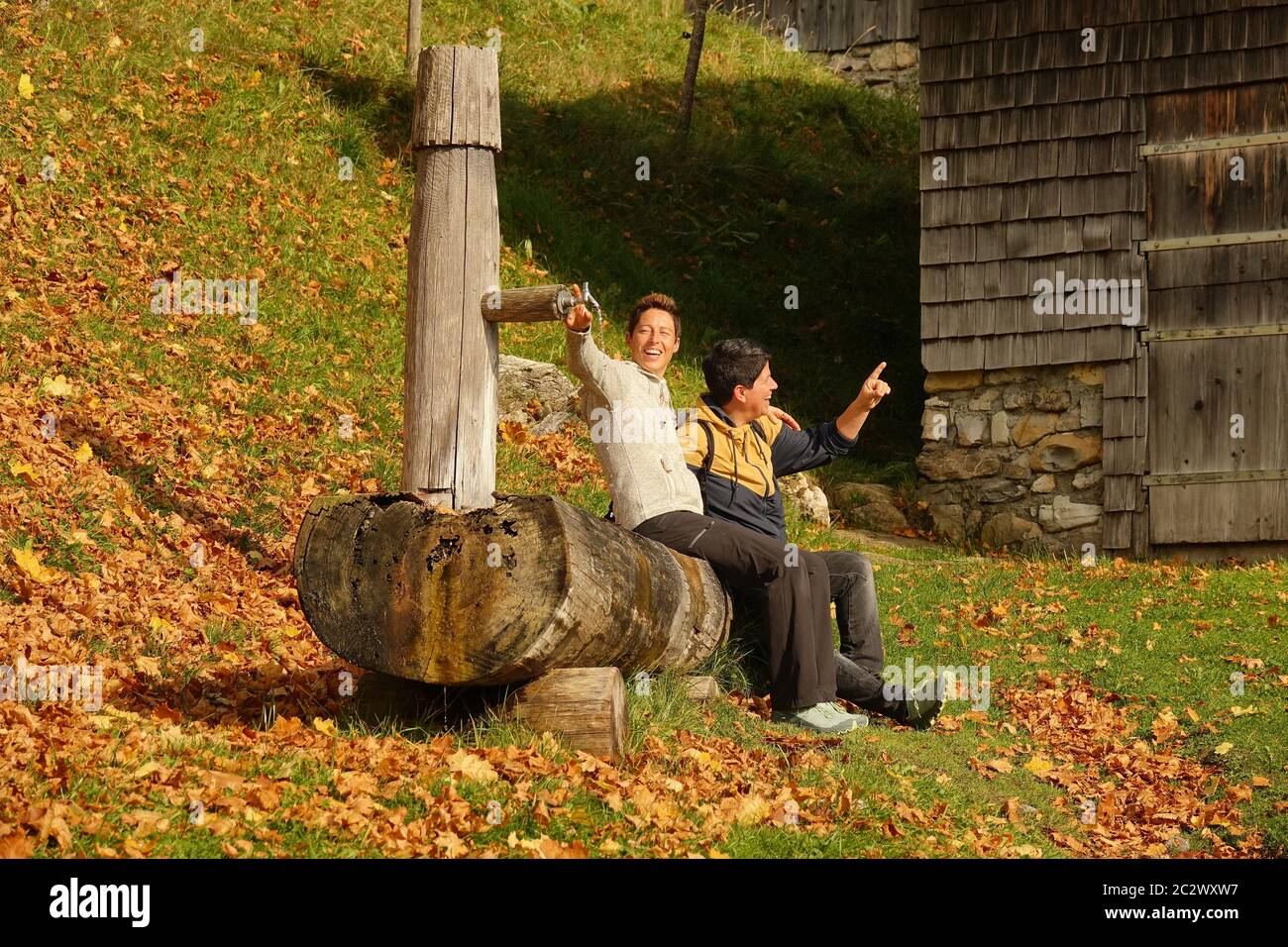 Deux femmes adultes sont assises sur le vieux puits de bois et Amuse-toi bien. Banque D'Images Deux femmes adultes sont assises sur le vieux puits de bois et Amuse-toi bien. Banque D'Images