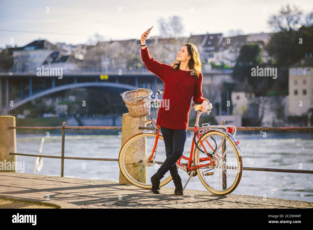 Une belle jeune femme avec un vélo rouge rétro fait une photo d'elle-même dans la vieille ville d'Europe sur l'éban du Rhin Banque D'Images