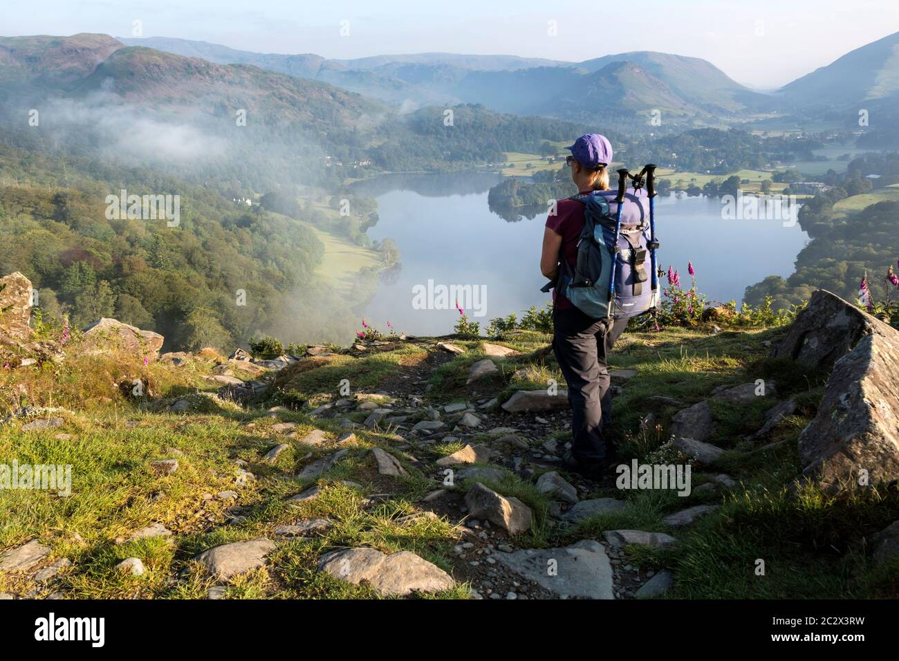 Walker appréciant la vue sur le lac Grasmere de Loughrigg est tombé sur un Misty matin d'été, Lake District, Cumbria, Royaume-Uni Banque D'Images