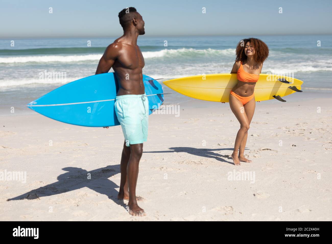 Couple heureux tenant des planches de surf sur la plage Banque D'Images