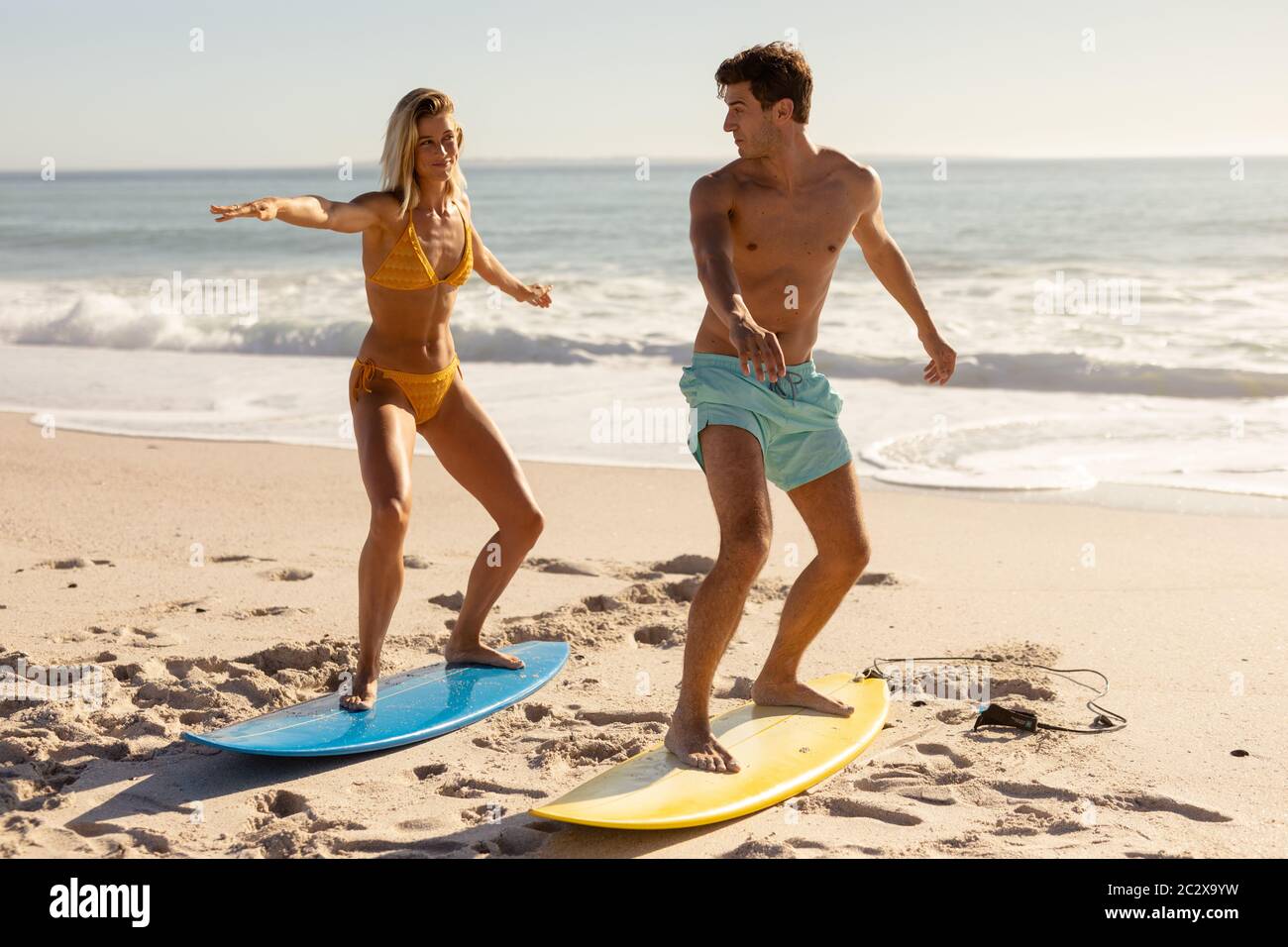 Un jeune couple surfant sur la plage Banque D'Images
