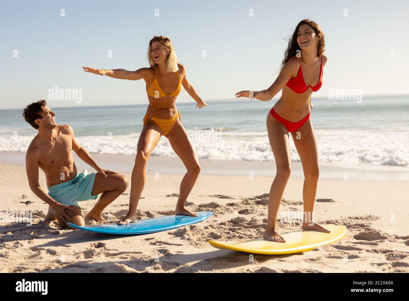 Groupe d'amis de race blanche surfant sur la plage Banque D'Images