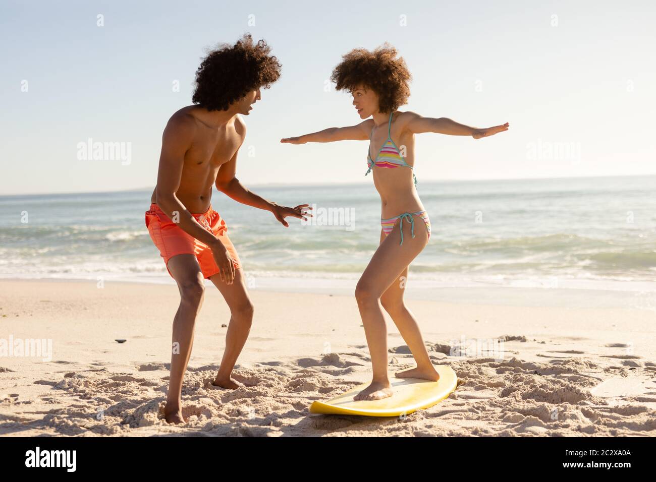 Un jeune couple surfant sur la plage Banque D'Images
