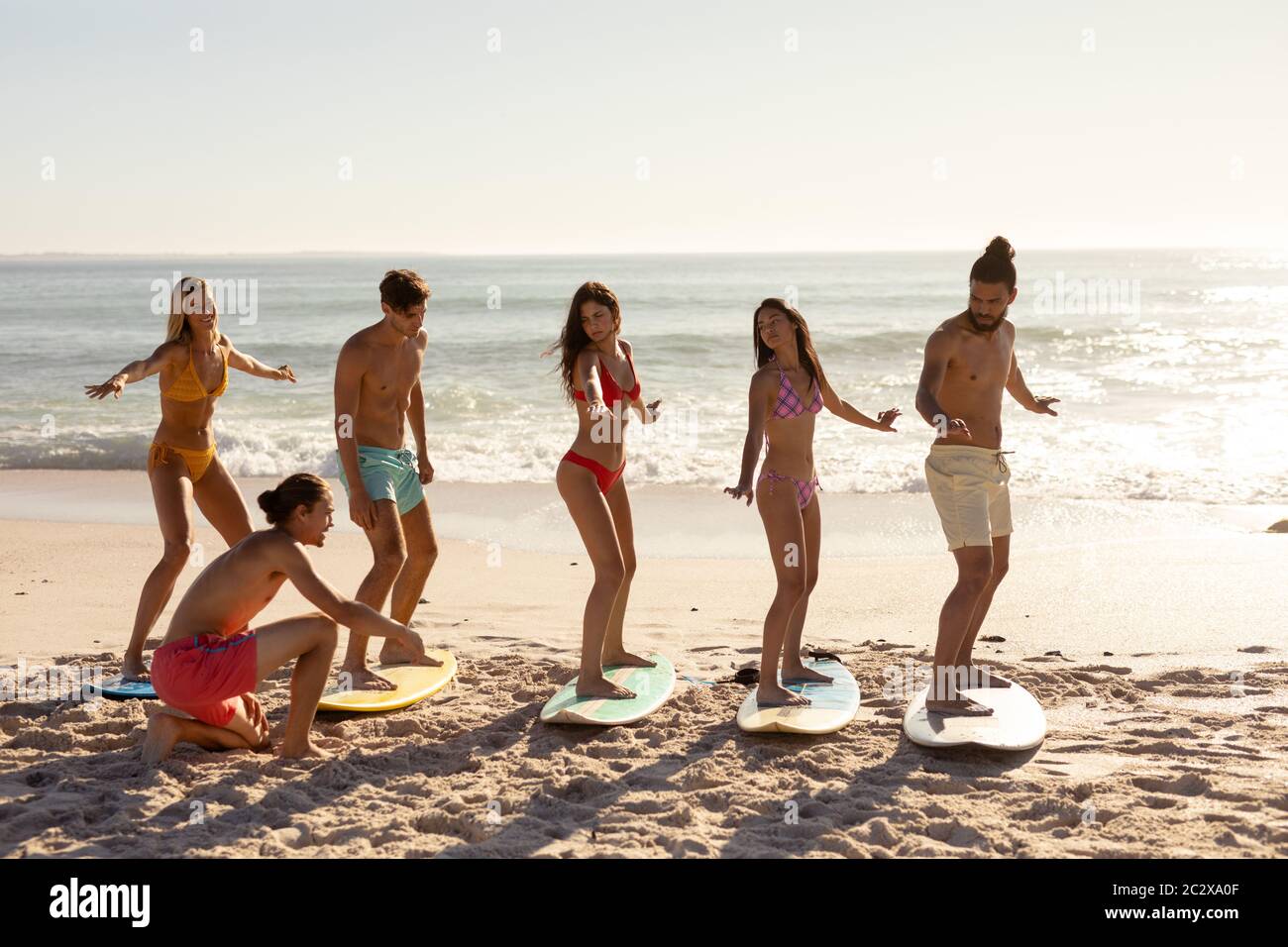 Groupe multiethnique de hommes et de femmes, surf sur la plage Banque D'Images