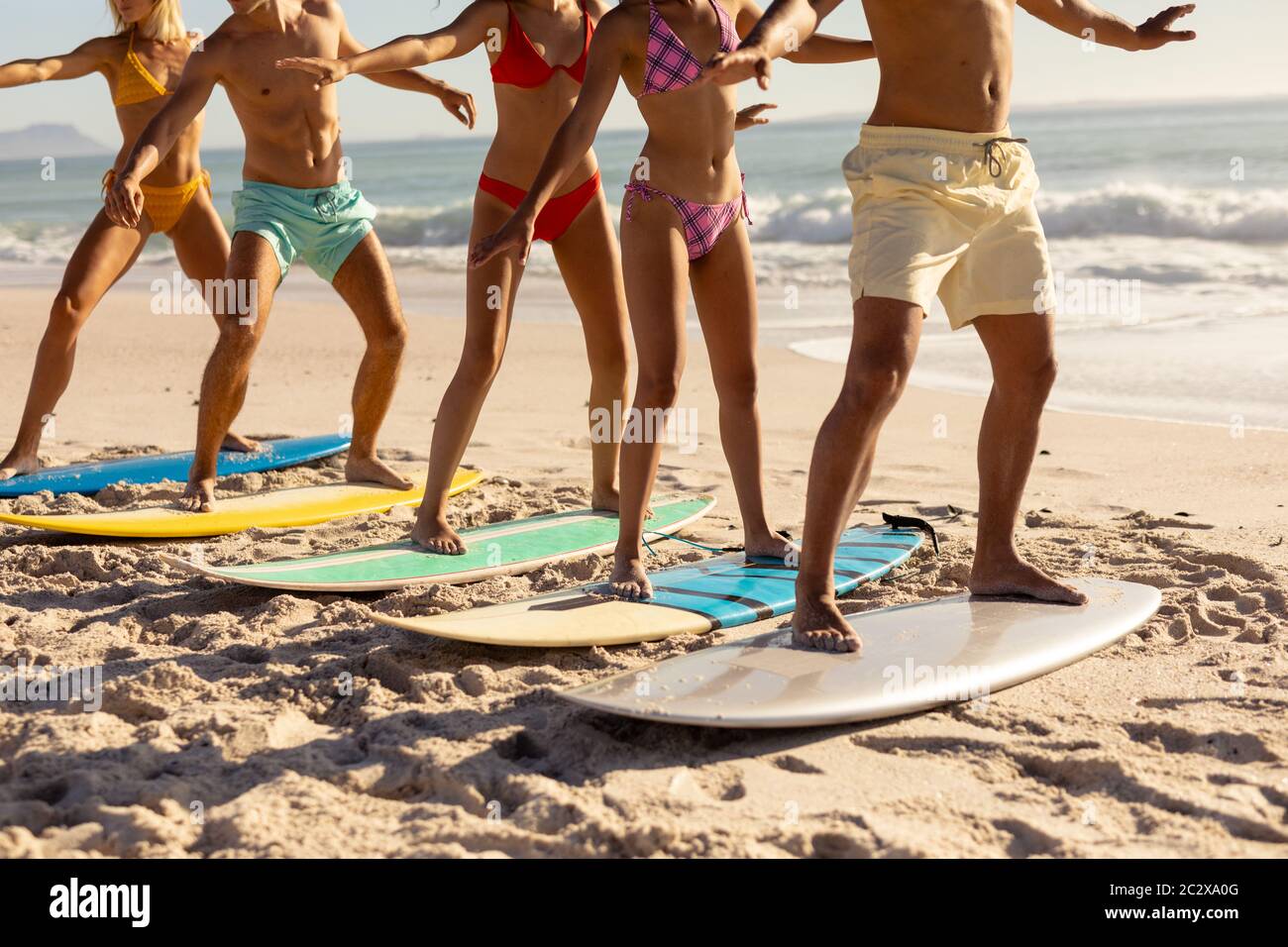 Groupe multiethnique de hommes et de femmes, surf sur la plage Banque D'Images