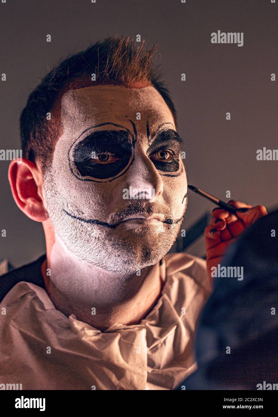 Artiste de l'application de peinture produits un jeune homme avant Halloween party Banque D'Images