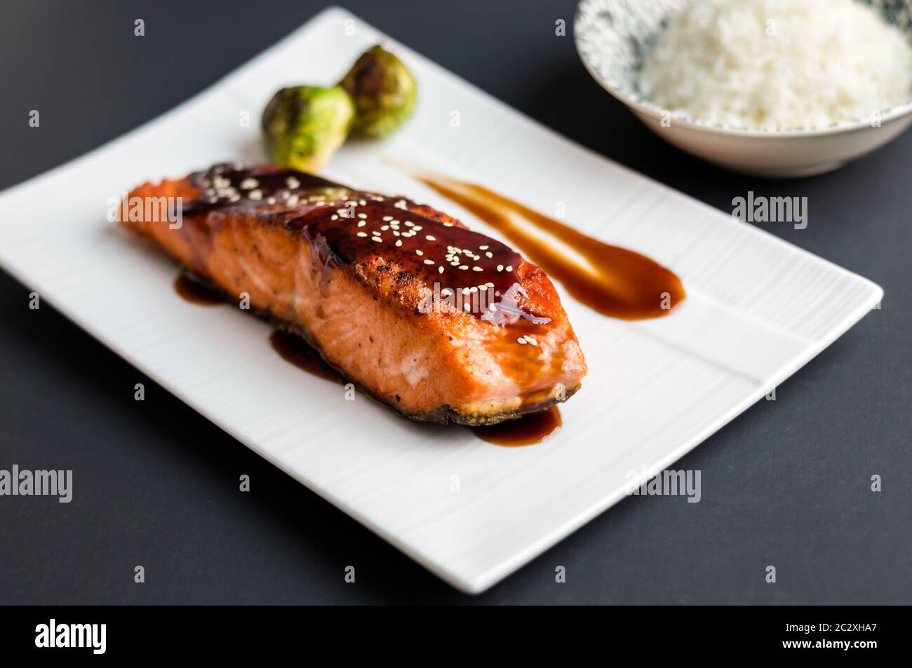 Cuisine japonaise cuisine inspirée de filets de saumon grillés, émaillés de délicieux mets teriyaki (base de sauce soja) et choux de Bruxelles sur une assiette blanche. Banque D'Images Cuisine japonaise cuisine inspirée de filets de saumon grillés, émaillés de délicieux mets teriyaki (base de sauce soja) et choux de Bruxelles sur une assiette blanche. Banque D'Images
