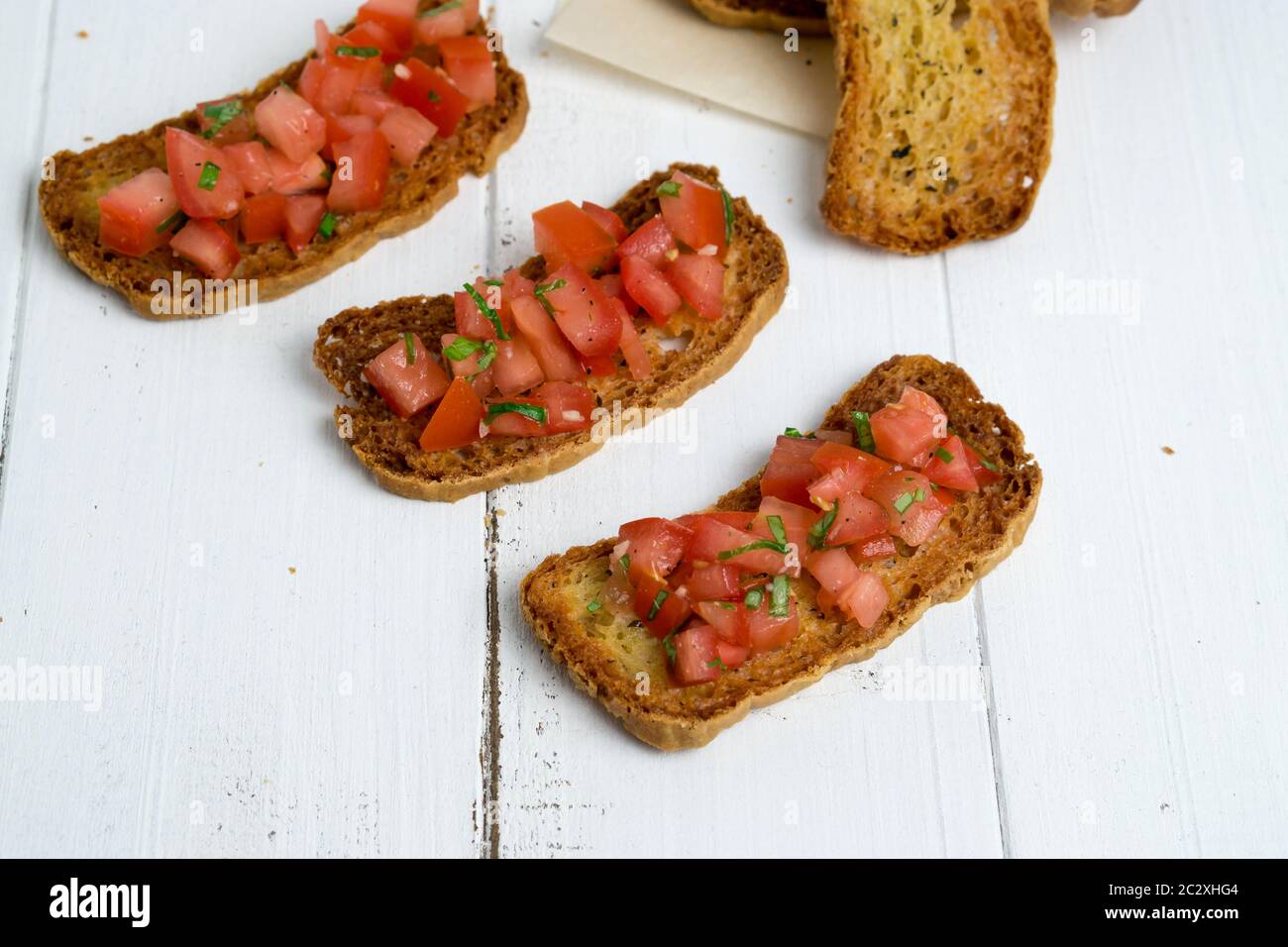 Bruschetta sur fond blanc. Bruschetta est un hors-d'œuvre italien populaire (antipasti), fait d'une crostini (pain grillé) avec des tomates en dés. Banque D'Images