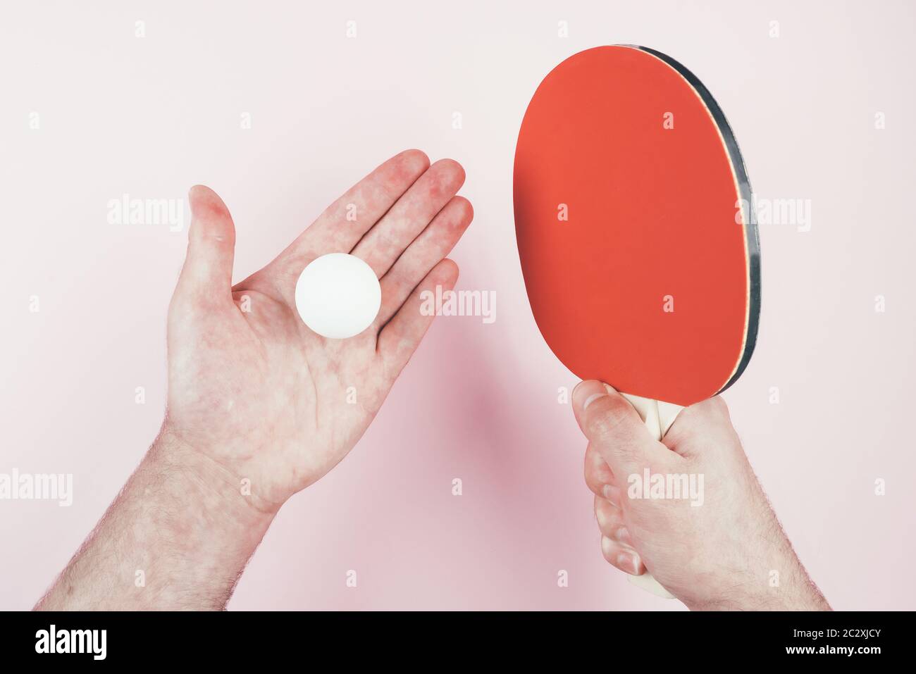 vue au-dessus de la personne tenant une balle de tennis de table dans une main et raquette dans l'autre sur fond rose Banque D'Images