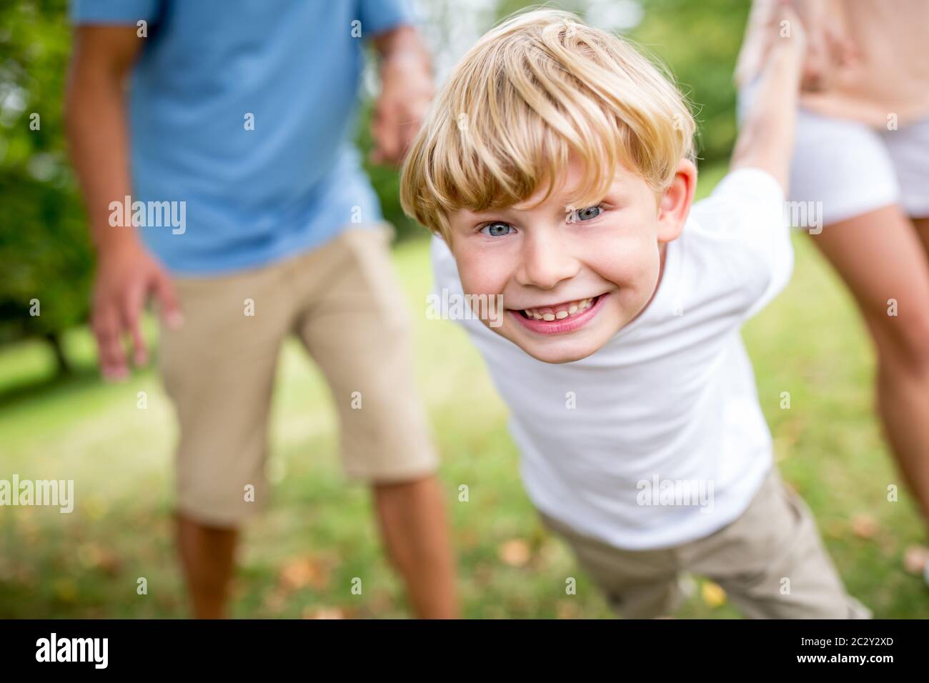 Un garçon qui rit joue avec sa famille dans le jardin en été Banque D'Images