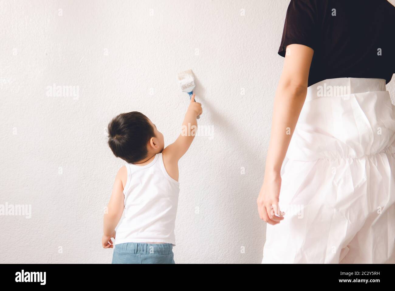 Petit enfant avec maman peignant le mur avec une brosse. Mère et fils. Banque D'Images