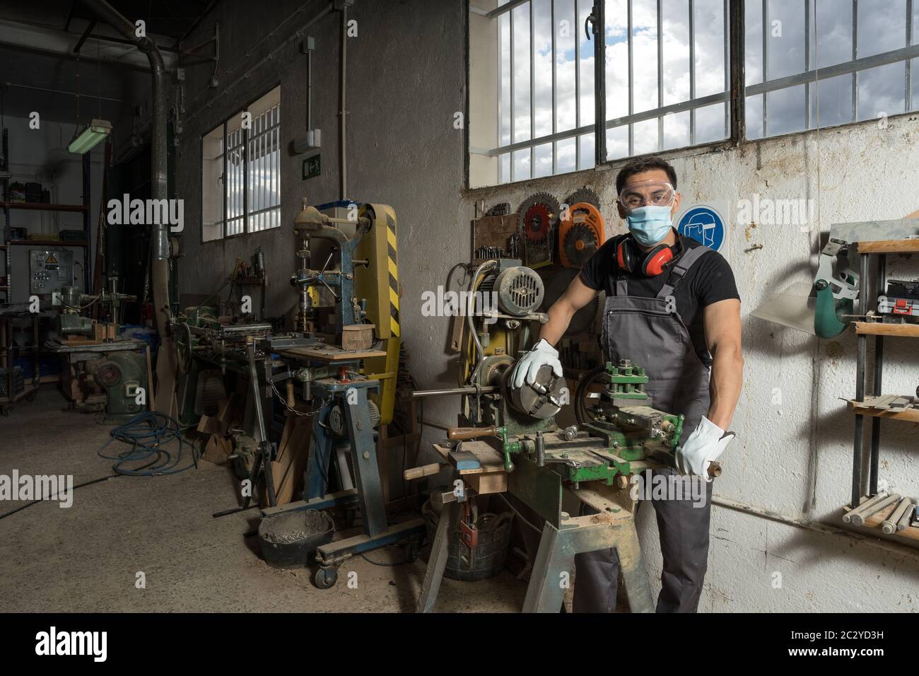 Travailleur debout avec un masque et un équipement de protection dans une usine. Photo intermédiaire. Banque D'Images