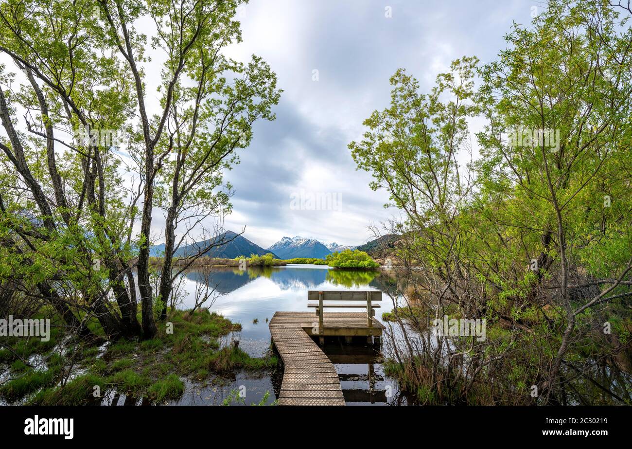 Jetée avec banc en bois au lac, montagnes reflétées dans le lac, Glenorchy Lagoon, Glenorchy, près de Queenstown, South Island, Nouvelle-Zélande Banque D'Images