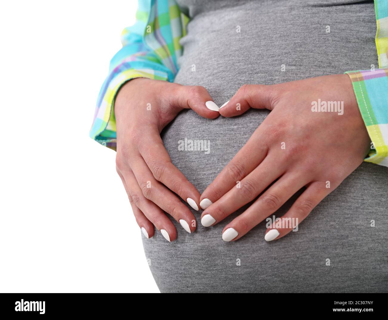 Vue de près de la moitié profil de la femme enceinte caucasienne tenant et touchant son ventre avec des mains en forme de coeur anticipant la naissance de bébé, isolée sur qui Banque D'Images