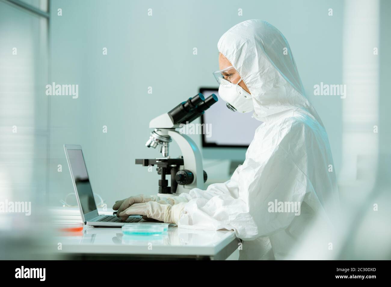 Un chercheur de laboratoire très occupé dans le domaine de la combinaison protectrice et du typage de masques respiratoires signale une infection à coronavirus en laboratoire Banque D'Images