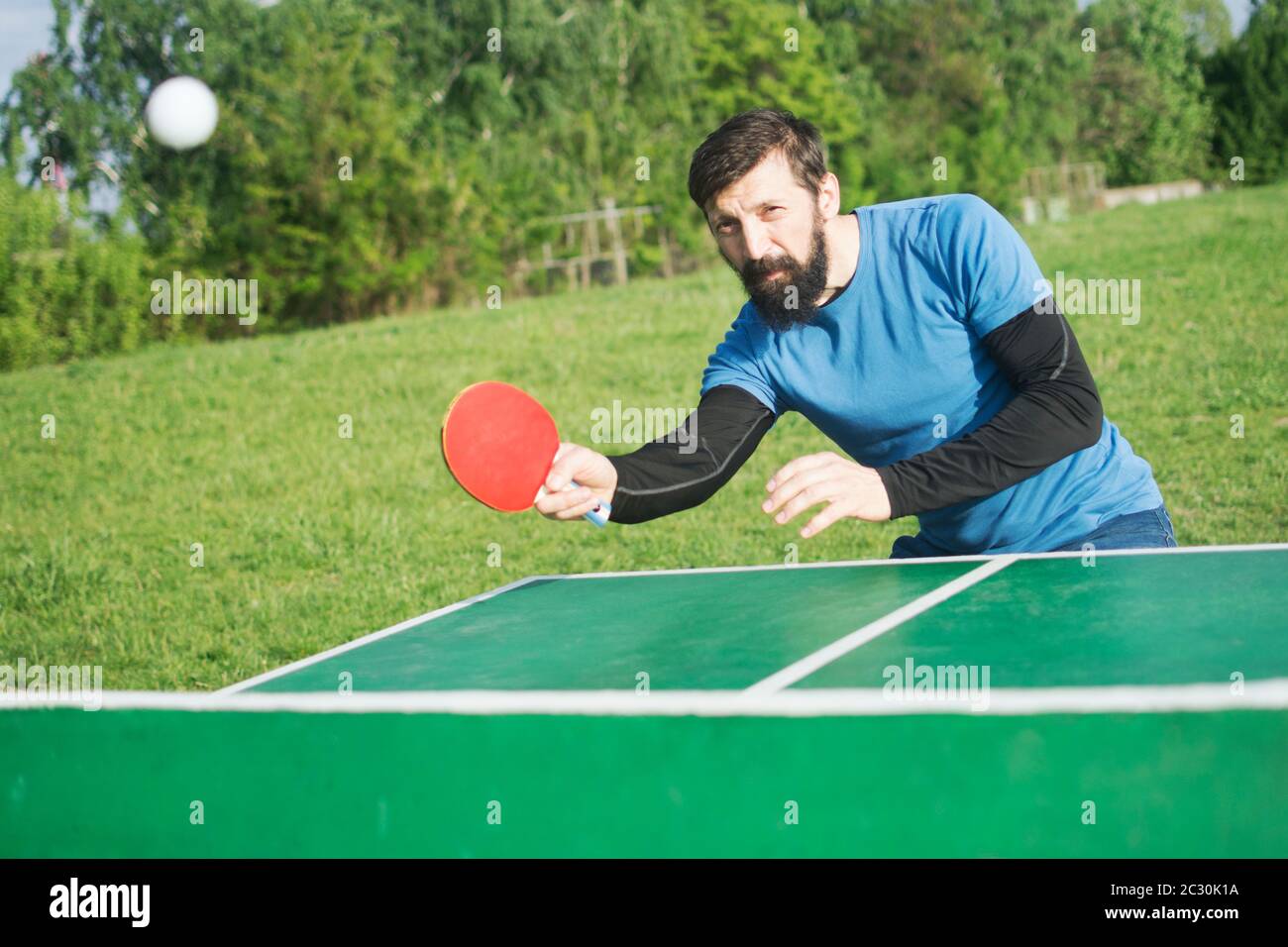 L'homme barbu joue au tennis de table ou au ping-pong en plein air comme  loisir Photo Stock - Alamy
