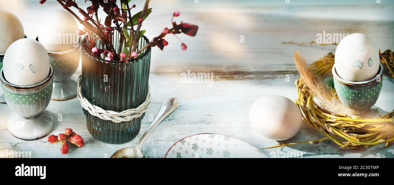 Petit déjeuner avec œufs de pâques. Encore une vie dans le style vintage avec des œufs pastel et des fleurs de printemps fraîches dans un vase sur bois gris. Wi en arrière-plan Banque D'Images