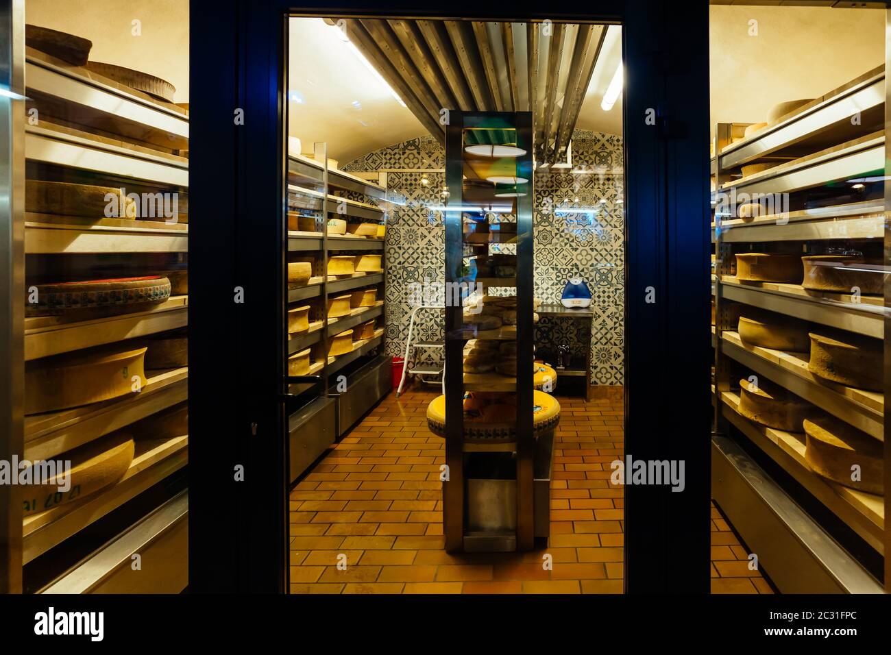 Grandes roues de fromage mûrissement dans la cave à produits laitiers de la maison de stockage Banque D'Images