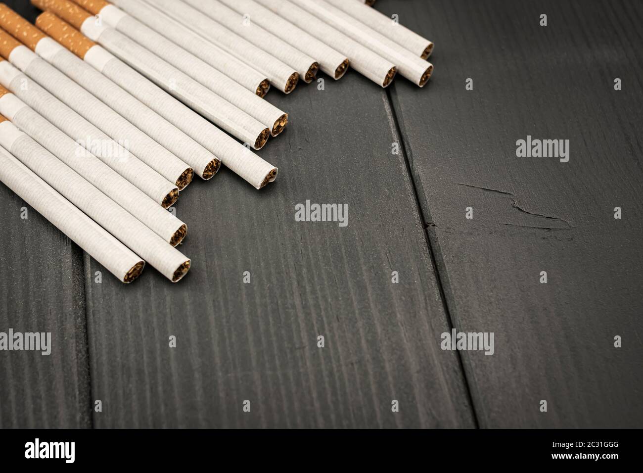 Cigarettes de tabac alignées dans le coin supérieur gauche sur fond gris en bois Banque D'Images