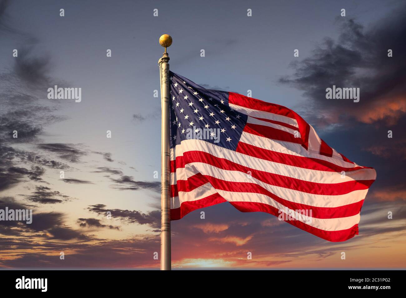 Un drapeau américain sur le flagpole se foulant dans le vent sous un ciel bleu clair Banque D'Images