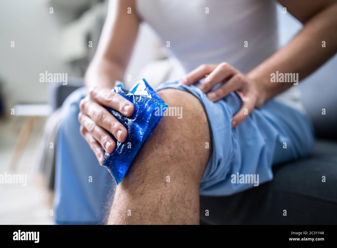 Close-up d'une personne assise à l'application de glace et de gel sur un genou blessé Banque D'Images