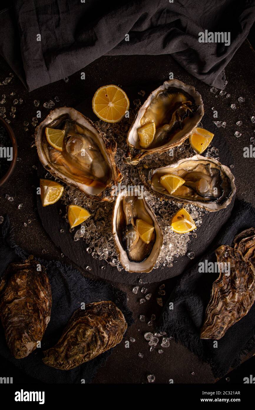 Huîtres servies sur un plateau d'ardoise noir avec glace et citron Photo  Stock - Alamy