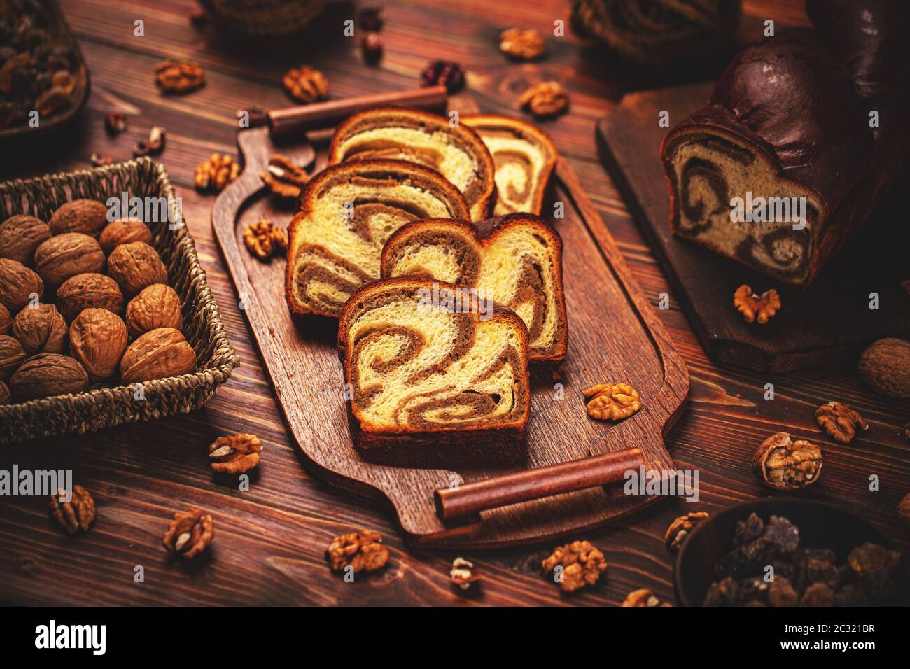 Gâteau au pain doux pain coupé en tranches garni de graines de noyer sur une planche de bois sur la table. Banque D'Images