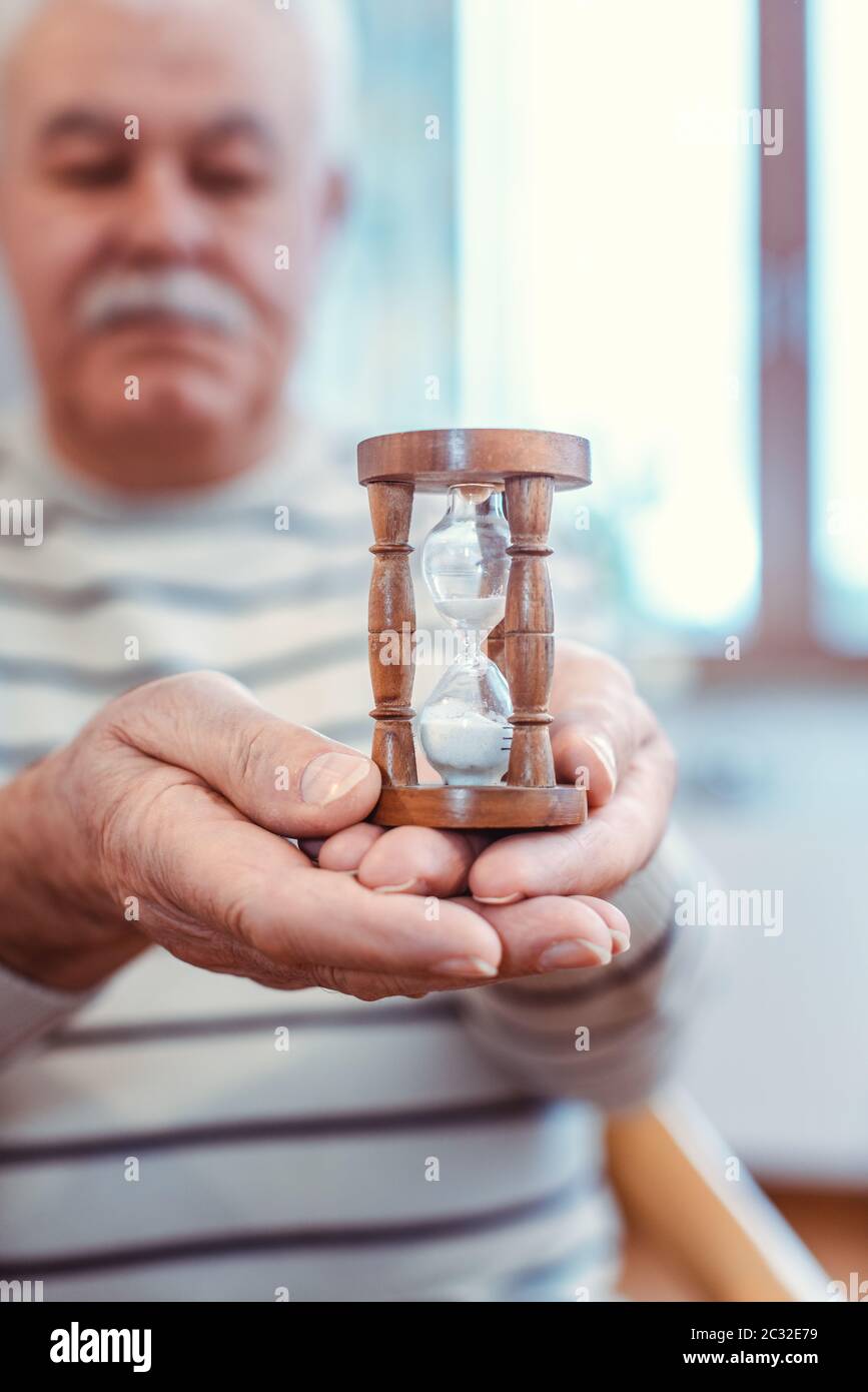 Homme âgé tenant un sablier dans une maison de retraite, symbole pour une durée de vie limitée Banque D'Images