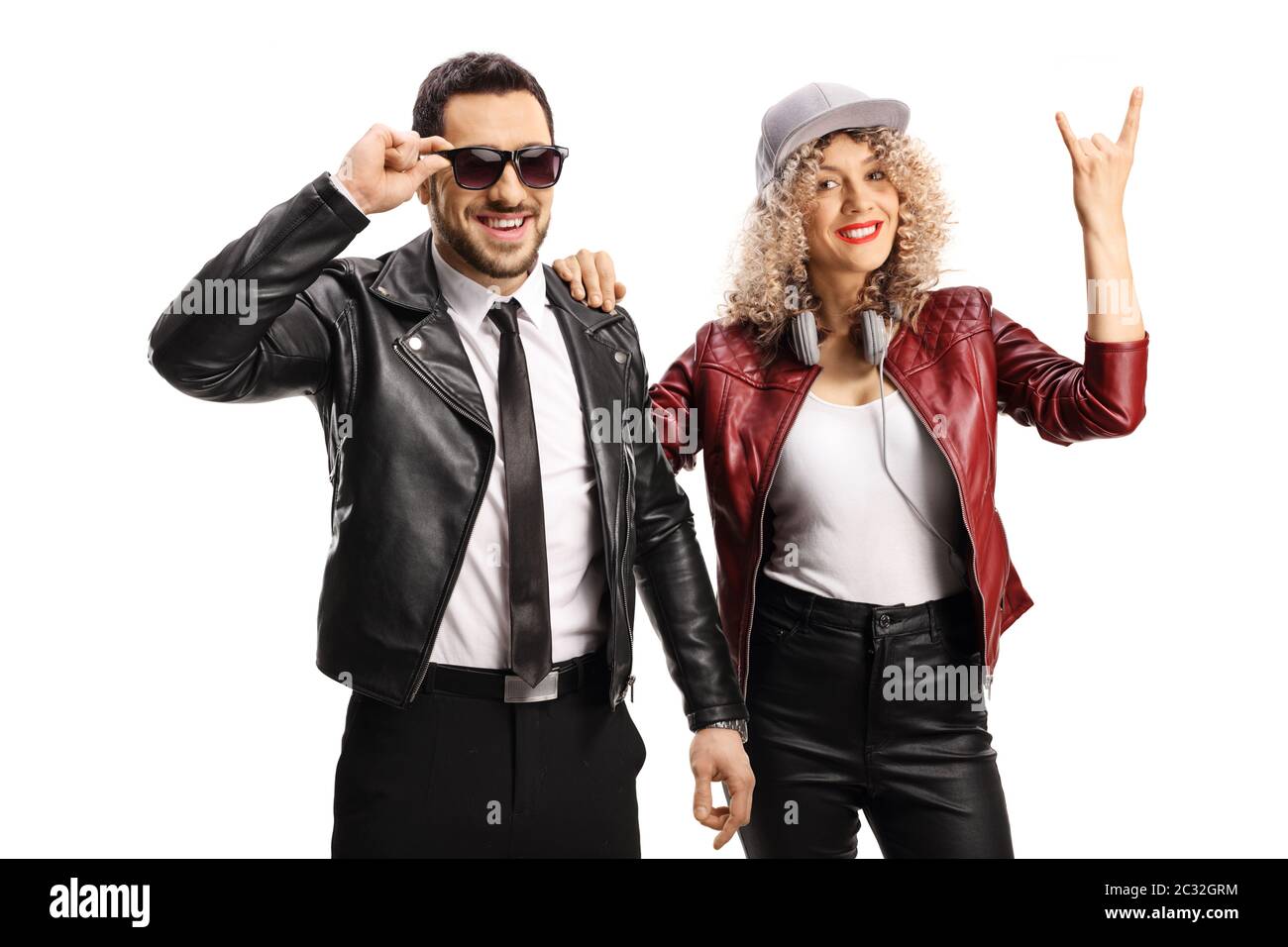 Jeune femme qui fait le geste d'un panneau de rock and roll et qui se penche sur un gars dans une veste en cuir et des lunettes de soleil isolées sur fond blanc Banque D'Images