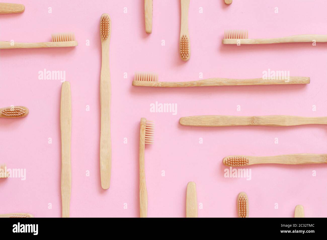 Vue de dessus de la disposition composée avec des brosses à dents en bambou zéro déchet organique sur fond rose Banque D'Images