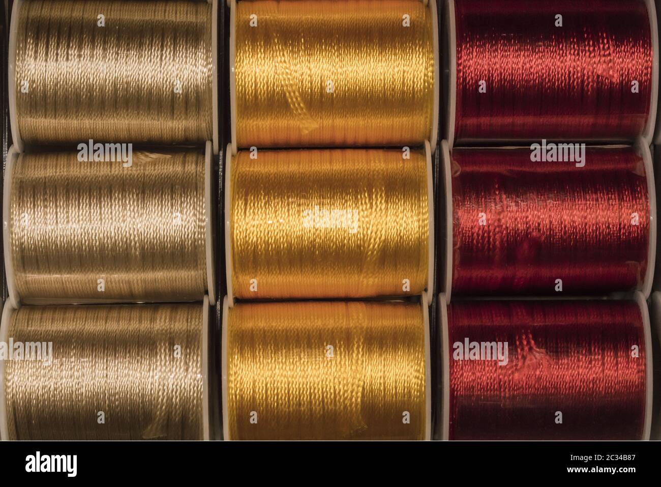 Gros plan sur la texture découpe de bobines de fils à coudre de couleur or, jaune et rouge. Banque D'Images