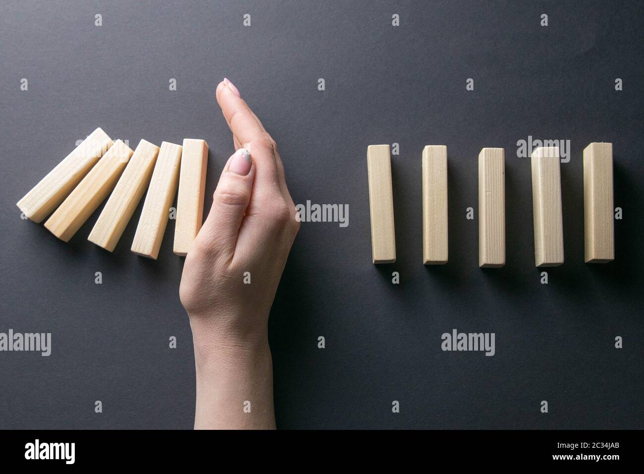 Vue de dessus de la main de l'arrêt de la chute des dominos dans une image conceptuelle de gestion de crise d'entreprise. Banque D'Images