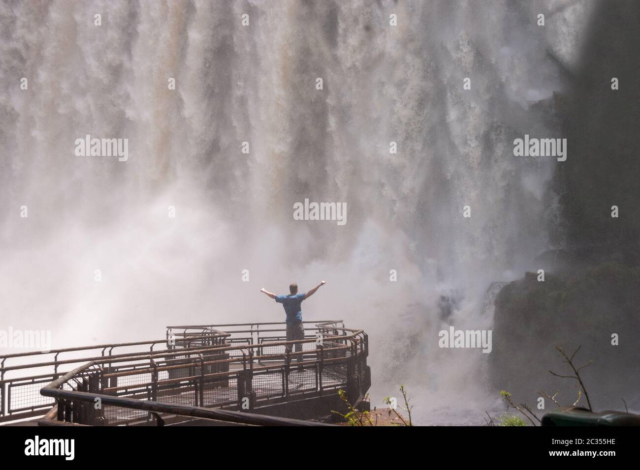 Homme debout près des chutes d'Iguaçu mains vers le haut po Banque D'Images