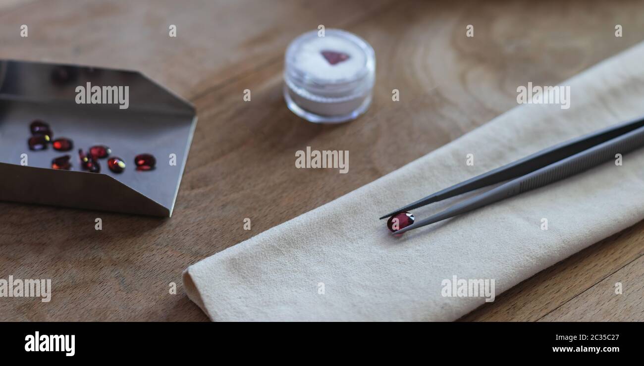 Table de travail gemmologie avec brucelles, daim et pelle avec pierres rubis Banque D'Images
