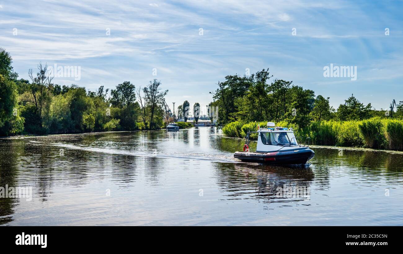 Le bateau gonflable à moteur flotte sur une rivière, entouré de roseaux et de tentatives, belle journée d'été sur la marina de bateaux de Szczecin, Pologne Banque D'Images