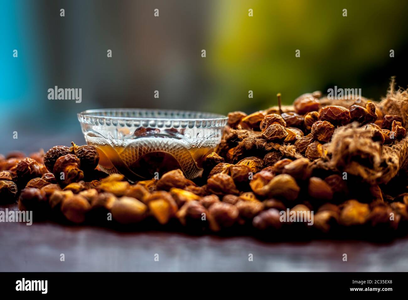 Gros plan de la soaécrou brut et de sa solution dans un bol en verre sur une surface en bois marron, plan avec un arrière-plan bokeh flou. Banque D'Images