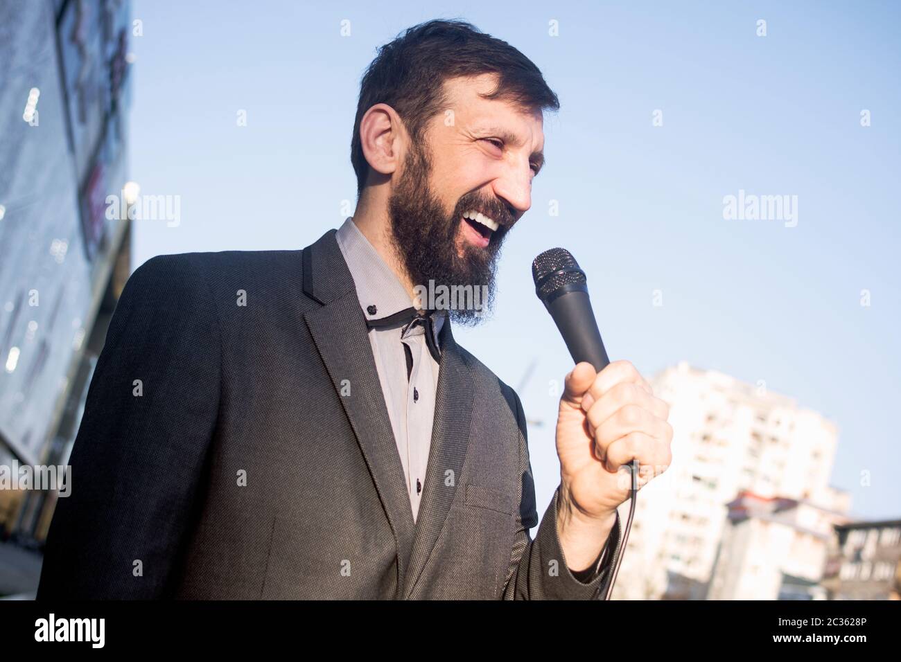 Le journaliste souriant de la télévision parle dans le microphone dans la rue. Banque D'Images