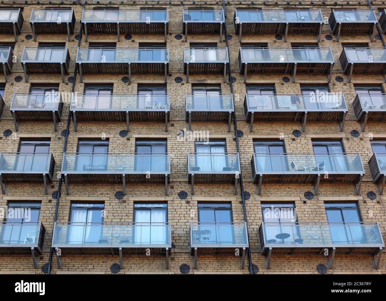 la façade d'un grand ancien moulin en pierre s'est transformée en appartements avec des balcons modernes en verre Banque D'Images
