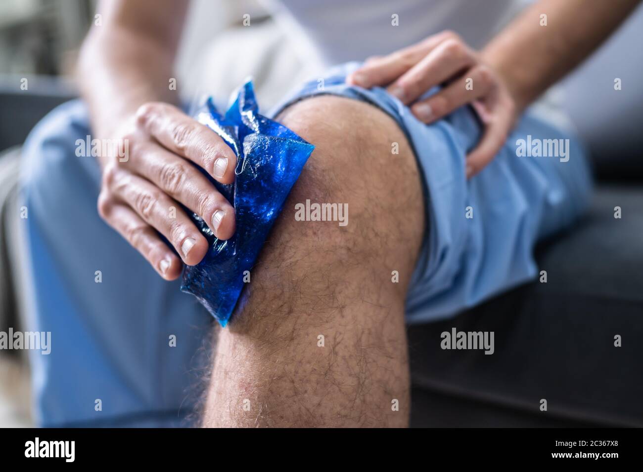 Close-up d'une personne assise à l'application de glace et de gel sur un genou blessé Banque D'Images