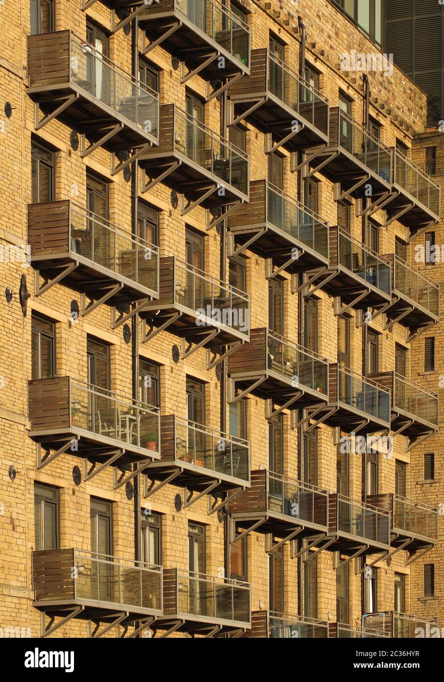 vue en perspective de la façade d'un grand ancien moulin en pierre transformé en appartements avec balcons modernes en verre Banque D'Images