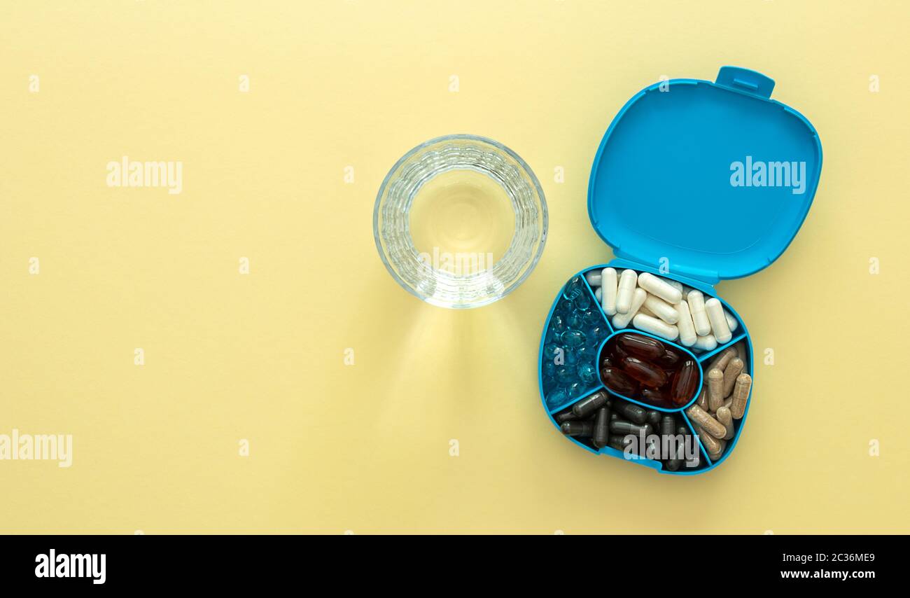 Boîte de rangement pour pilules avec verre d'eau. Concept de santé. Banque D'Images