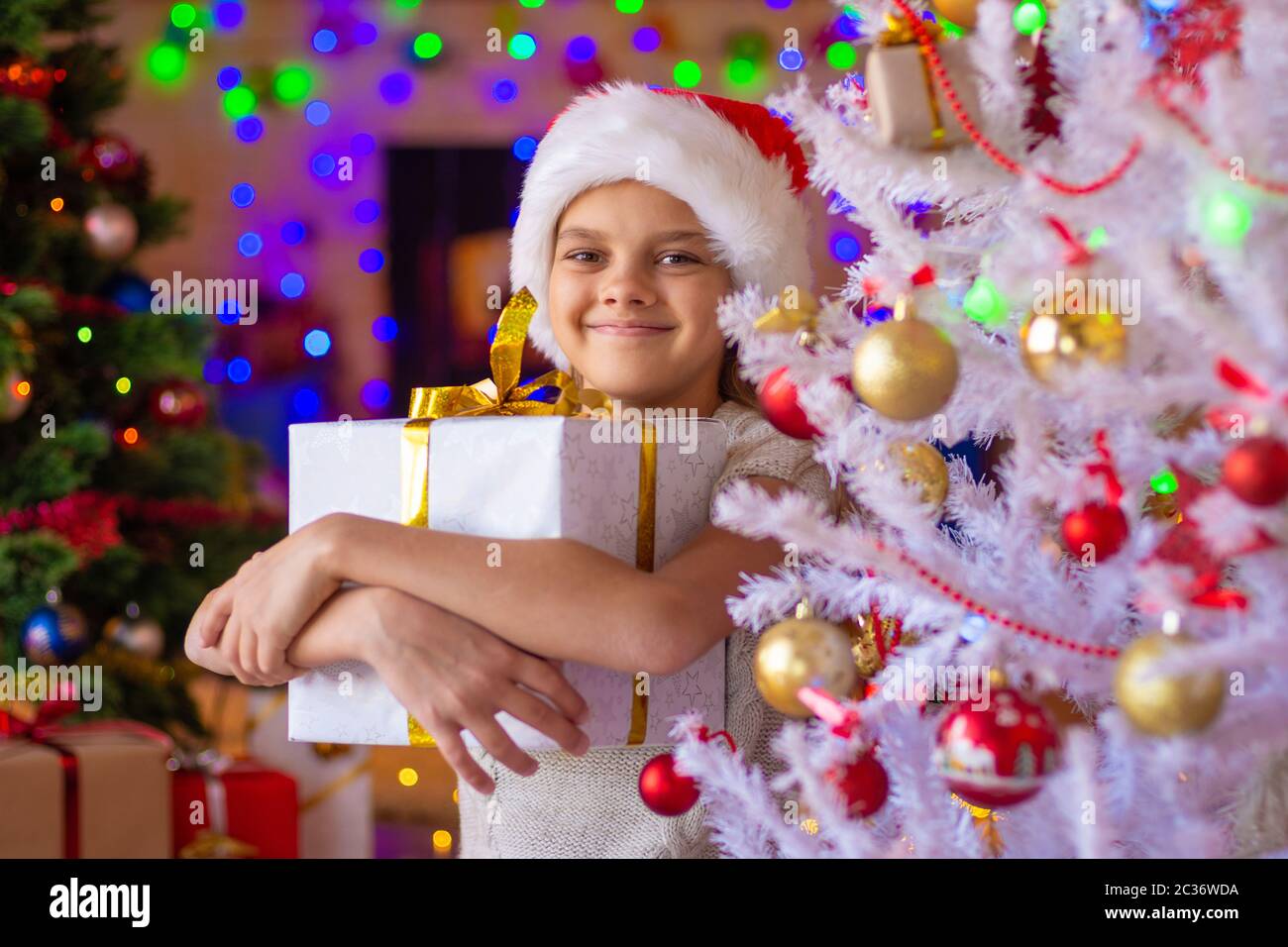 Bonne fille avec un cadeau dans un arbre de Noël blanc Banque D'Images