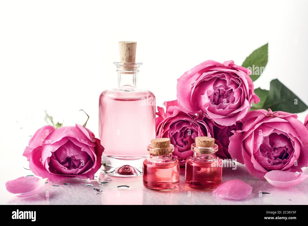 Eau de rose parfumée dans une bouteille de verre, huile et roses. Banque D'Images