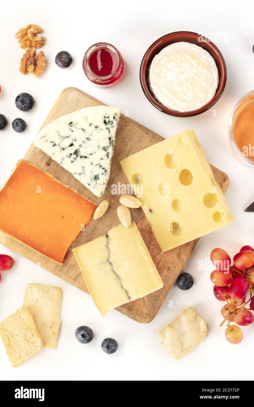 Plateau de fromages, plan plat sur fond blanc. Fromage bleu, fromage hollandais et autres, une variété de fruits et de noix Banque D'Images