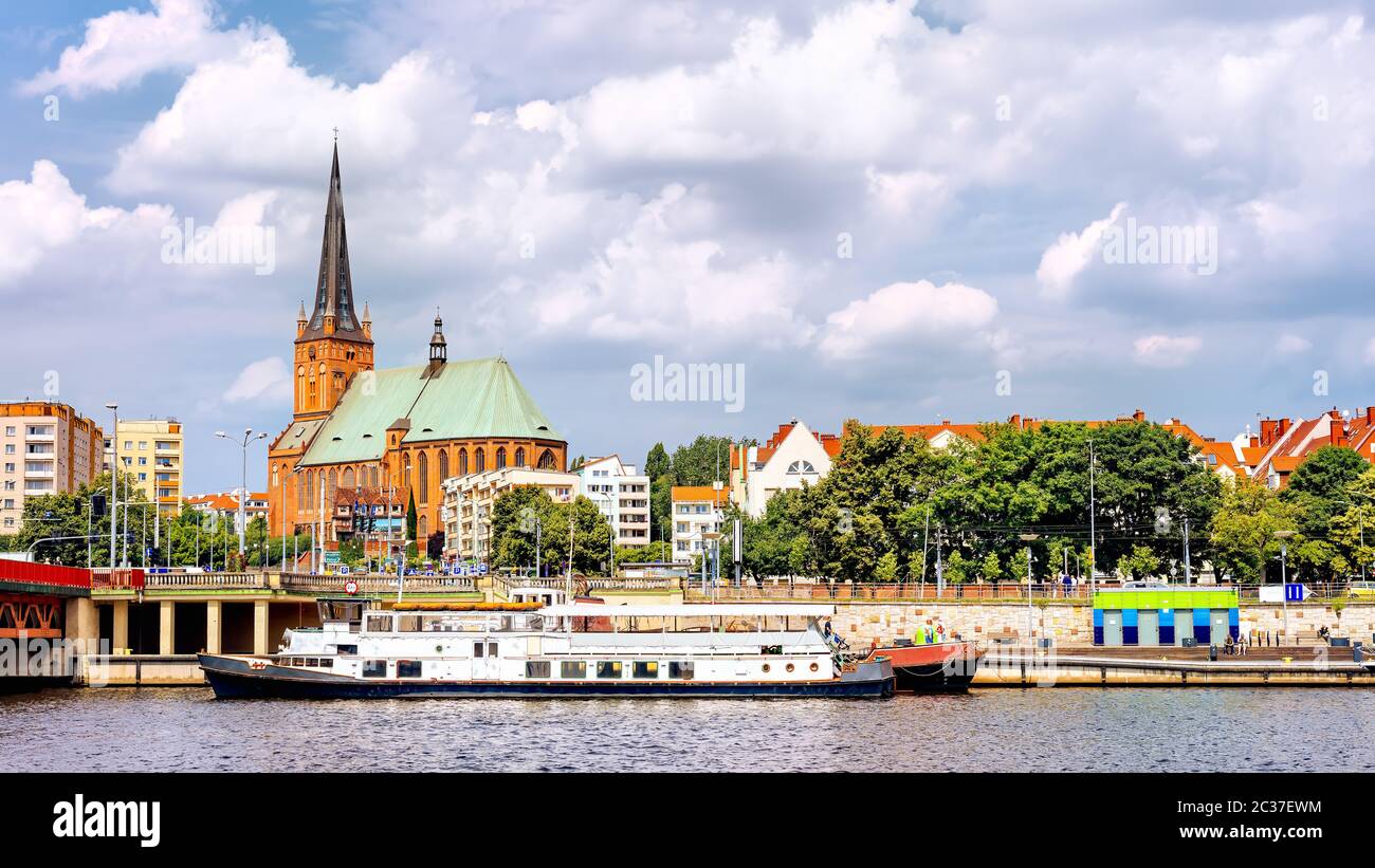 Navires ancrés sur la jetée de la rivière Odra. Les gens se détendant sur le boulevard Piastowski. Cathédrale Basilique St James l'Apôtre en arrière-plan, Szczecin, Pologne Banque D'Images