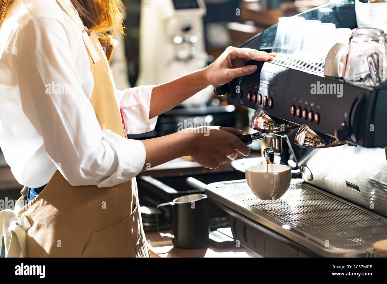gros plan d'un café de barista préparé par une machine à café moderne pour préparer une tasse de café avec d'autres barista travaillant en arrière-plan. Utilisation de pour Banque D'Images