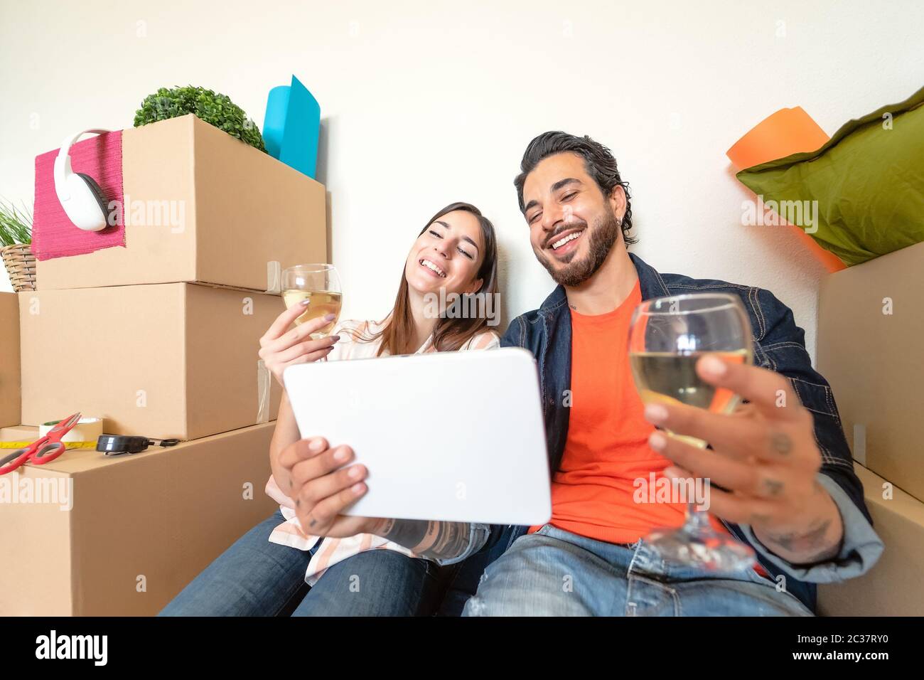Jeune couple déménagent dans une nouvelle maison de propriété - heureux amoureux ayant plaisir à faire des achats en ligne avec tablette numérique dans la nouvelle maison Banque D'Images