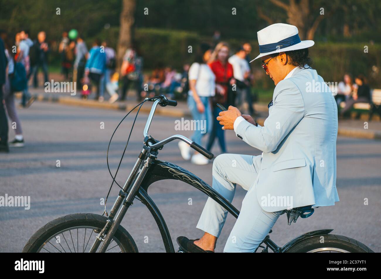 Moscou, Russie - 1er mai 2018. Homme d'affaires tendance dans un chapeau, veste légère sur un vélo, regardant le téléphone, contre le bac Banque D'Images