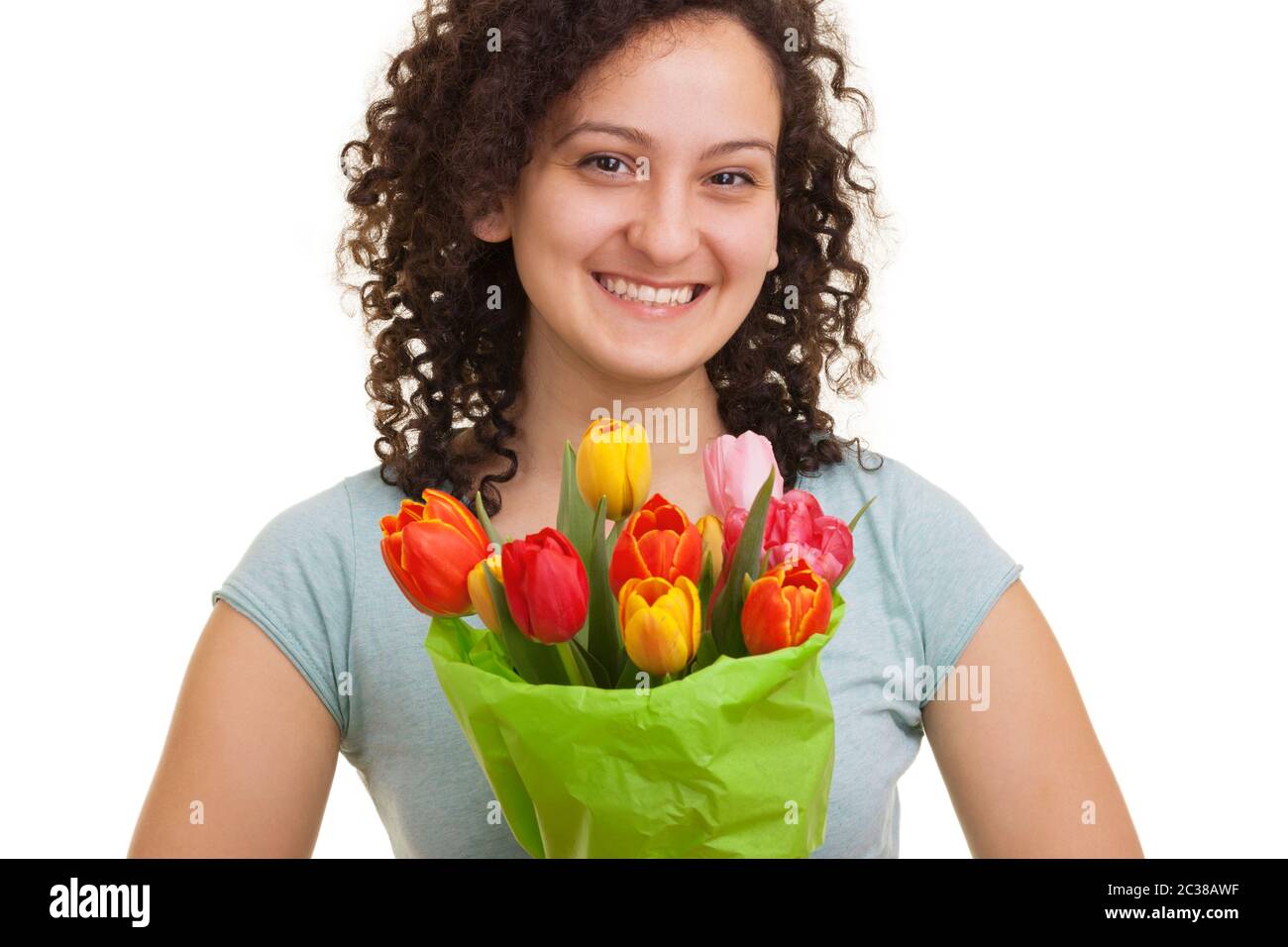 Jeune femme naturelle avec cheveux bouclés tenant un bouquet de tulipes colorées, isolée sur fond blanc. Fête des mères, Saint-Valentin Banque D'Images