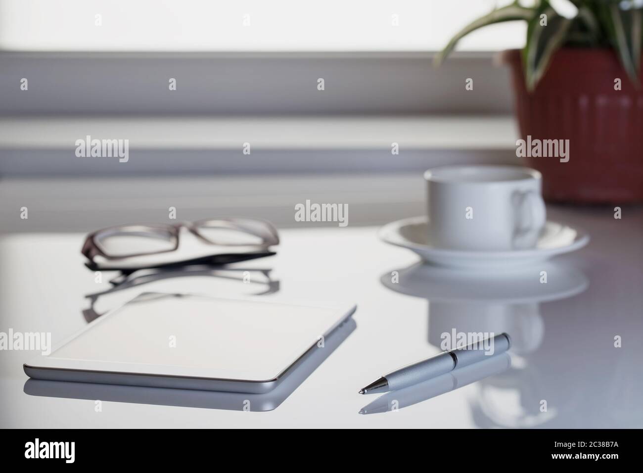 Tablet computer, verres et stylo sur la table avec une fleur. Retiré logos, boutons, changer la taille d'origine. Banque D'Images